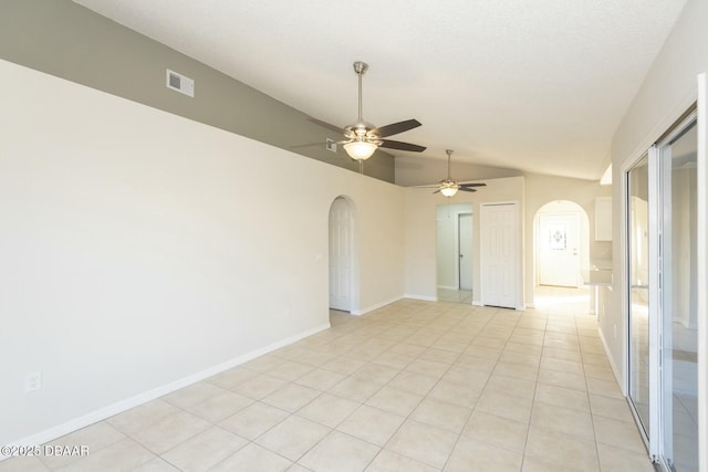 empty room with ceiling fan, lofted ceiling, and light tile patterned floors