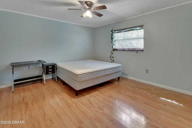 bedroom featuring ornamental molding, baseboards, a textured ceiling, a ceiling fan, and wood finished floors