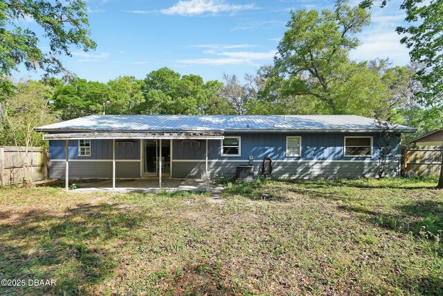 rear view of property with fence and metal roof
