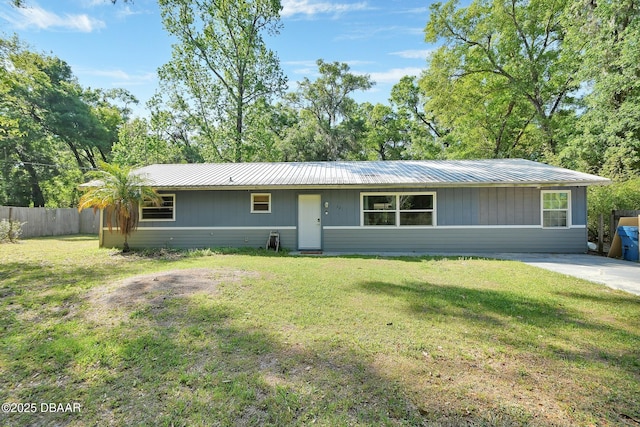 ranch-style home with metal roof, fence, and a front yard