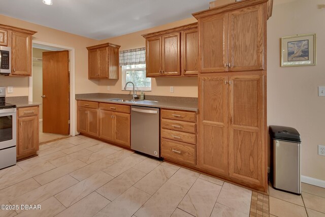 kitchen with brown cabinets, baseboards, a sink, and stainless steel appliances