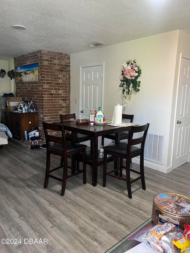 dining space with hardwood / wood-style floors and a textured ceiling