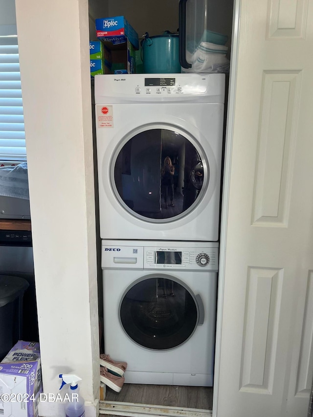 laundry area with stacked washer / drying machine and hardwood / wood-style floors