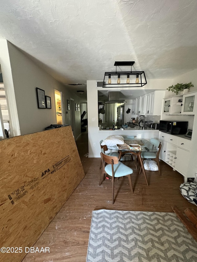 kitchen featuring sink, a textured ceiling, wood-type flooring, and white cabinets