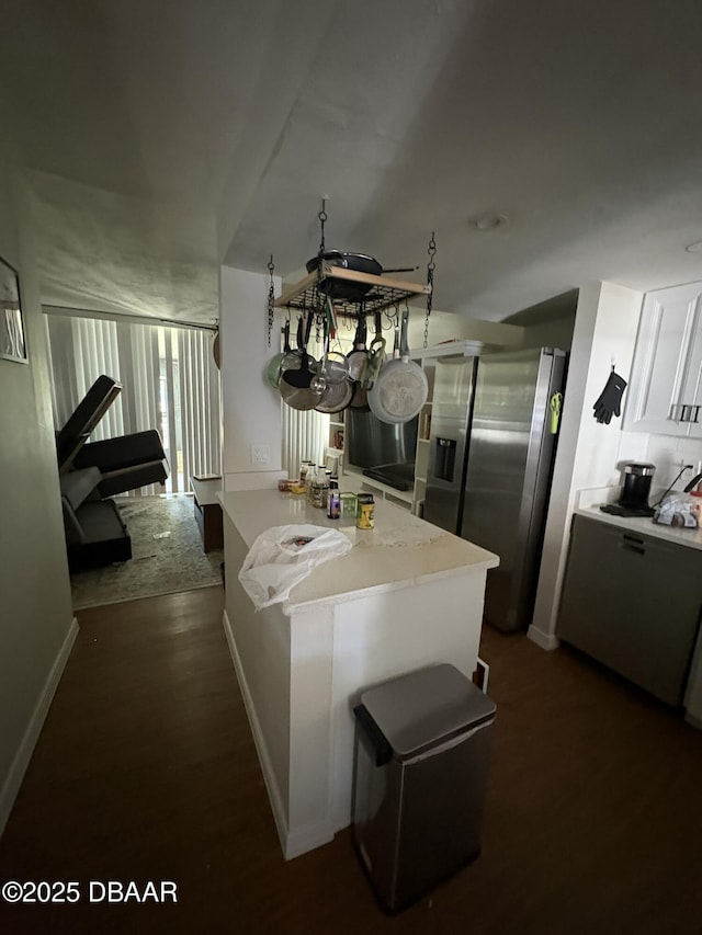 kitchen featuring tasteful backsplash, white cabinetry, stainless steel fridge, dark hardwood / wood-style flooring, and kitchen peninsula