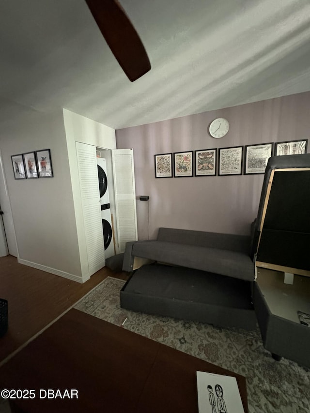 workout area with stacked washer / dryer and hardwood / wood-style flooring