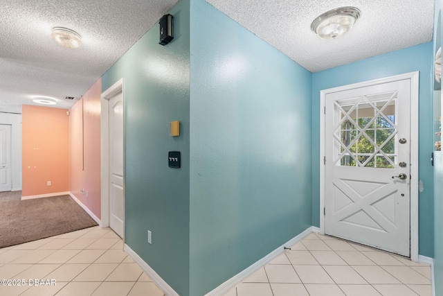 doorway to outside with light tile patterned floors, a textured ceiling, and baseboards