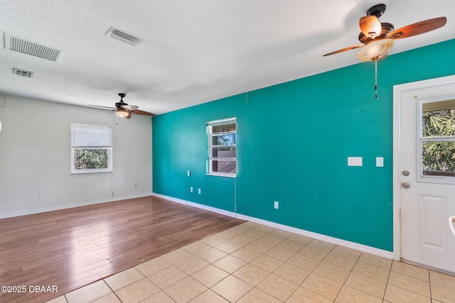 empty room with ceiling fan, visible vents, and a textured ceiling