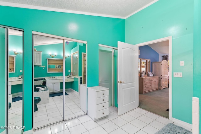 interior space featuring a textured ceiling, ornamental molding, vanity, and tile patterned flooring