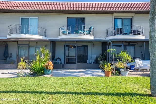 back of house with a yard, a balcony, and a sunroom