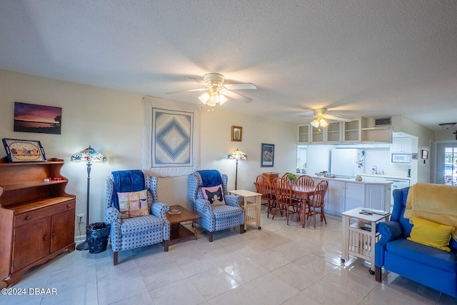 sitting room with ceiling fan, light tile patterned floors, and a textured ceiling