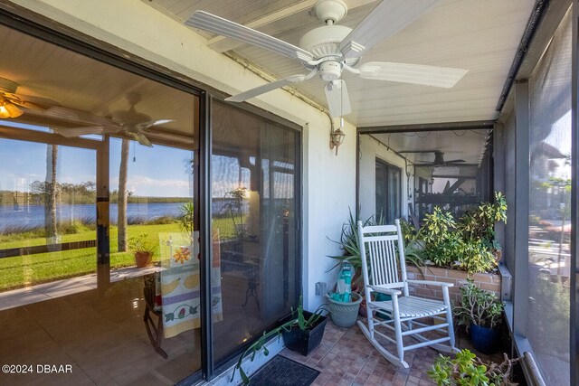 sunroom featuring ceiling fan and a water view