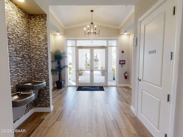 foyer with french doors, vaulted ceiling, light hardwood / wood-style flooring, wooden ceiling, and a chandelier