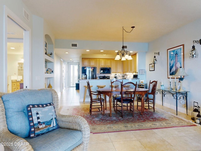 dining room featuring built in features, light tile patterned floors, and an inviting chandelier