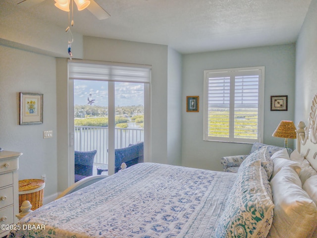 bedroom featuring ceiling fan, access to exterior, a textured ceiling, and a water view