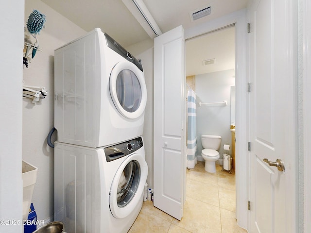 laundry area featuring light tile patterned floors and stacked washer and clothes dryer