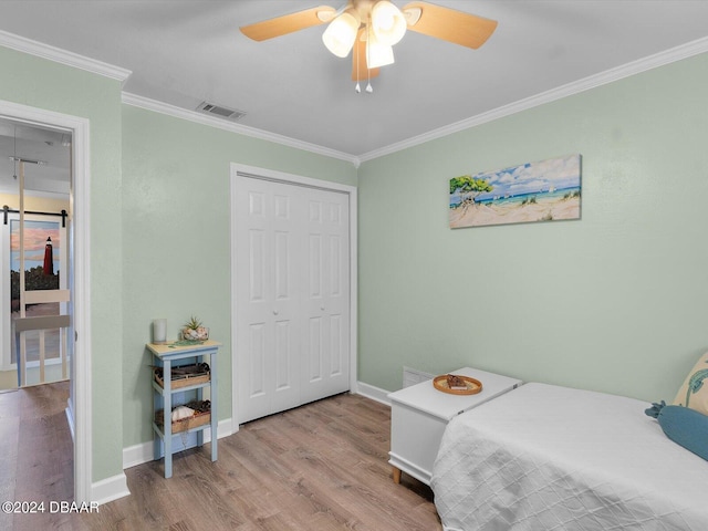 bedroom featuring ornamental molding, a closet, light hardwood / wood-style floors, and ceiling fan