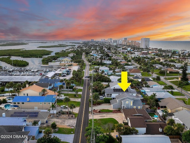 aerial view at dusk featuring a water view