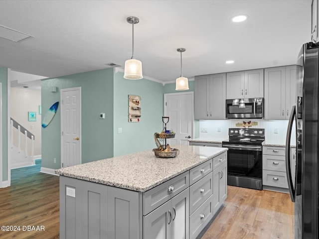 kitchen featuring appliances with stainless steel finishes, decorative light fixtures, a center island, gray cabinetry, and light wood-type flooring