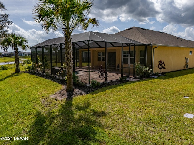 rear view of property with a lanai, a lawn, and a patio