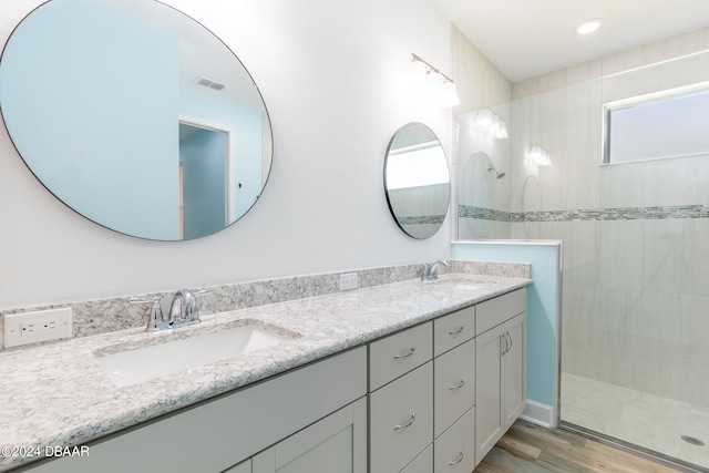 bathroom featuring tiled shower, wood-type flooring, and vanity