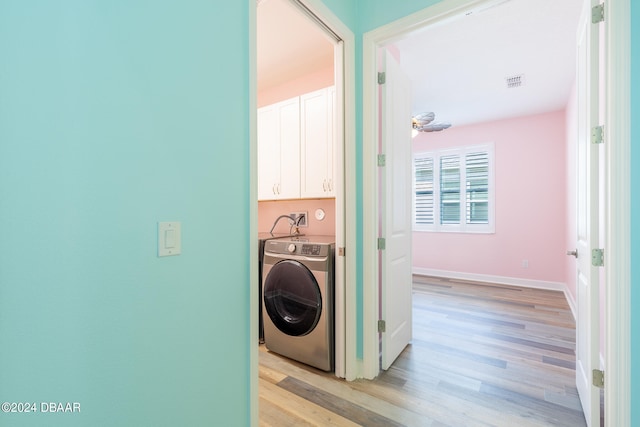 laundry room featuring washer / clothes dryer, cabinets, and light hardwood / wood-style flooring