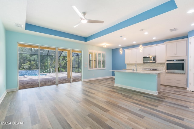 kitchen featuring a center island with sink, appliances with stainless steel finishes, light hardwood / wood-style floors, white cabinets, and ceiling fan