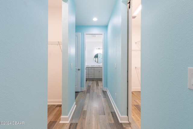 hallway with a barn door and light hardwood / wood-style floors