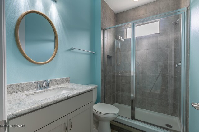 bathroom with an enclosed shower, vanity, and toilet