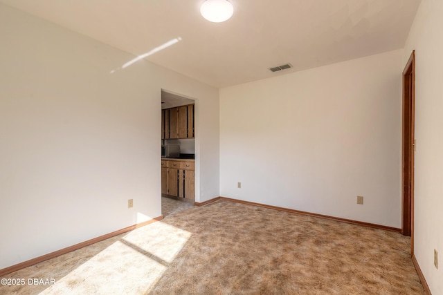 unfurnished room with visible vents, light carpet, and baseboards