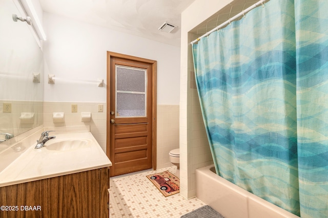 bathroom with visible vents, vanity, shower / bath combo, tile patterned floors, and tile walls