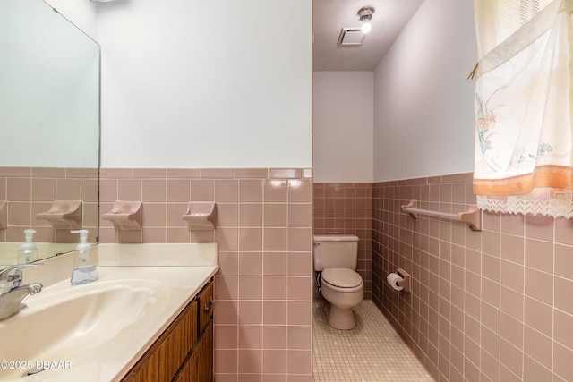 half bathroom featuring visible vents, tile walls, toilet, tile patterned floors, and vanity