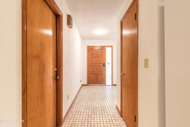 corridor featuring baseboards and light tile patterned flooring