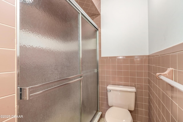 full bathroom featuring tile walls, toilet, a wainscoted wall, and a shower stall