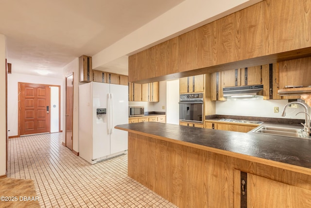 kitchen with under cabinet range hood, black oven, stainless steel microwave, dark countertops, and white refrigerator with ice dispenser