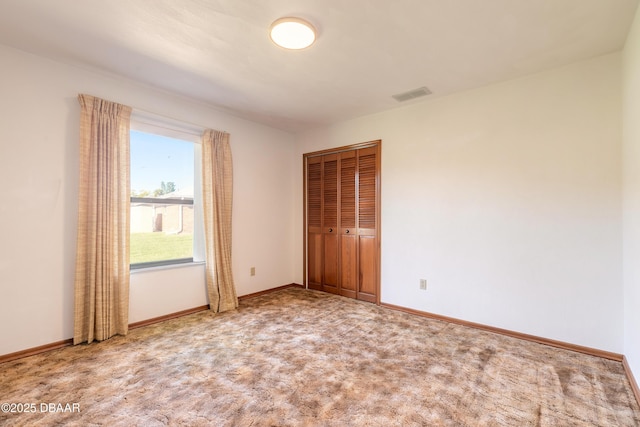 unfurnished bedroom featuring a closet, visible vents, carpet flooring, and baseboards