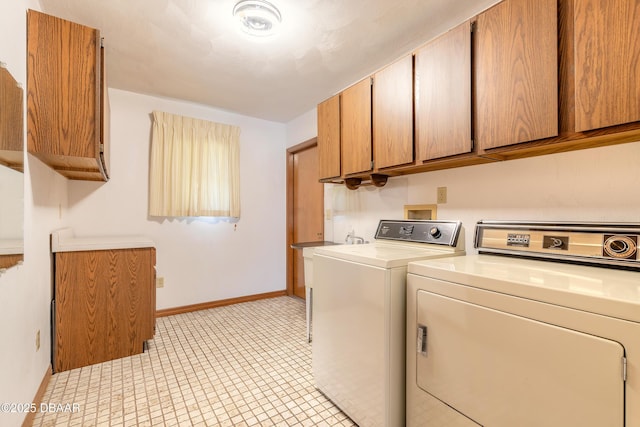 laundry room featuring separate washer and dryer, cabinet space, and baseboards