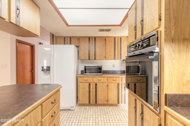 kitchen with visible vents, stainless steel microwave, dark countertops, white refrigerator with ice dispenser, and double oven