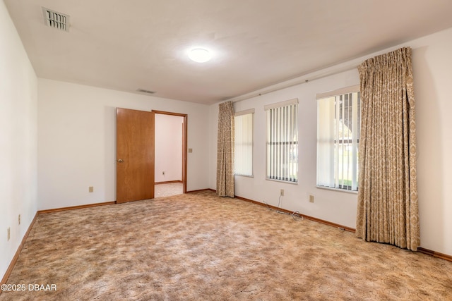 carpeted spare room with visible vents and baseboards