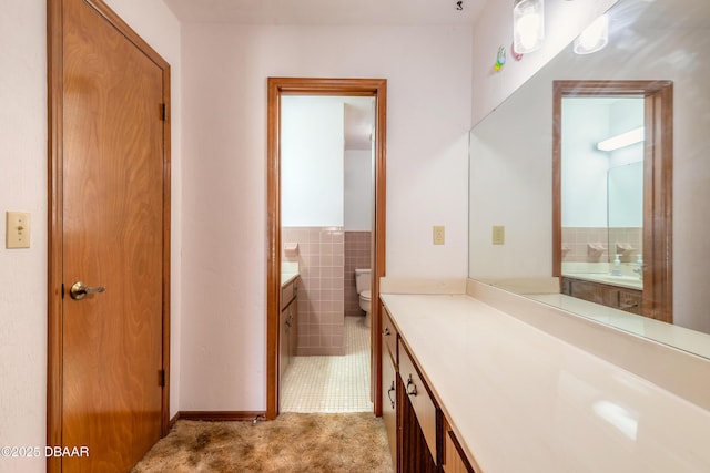 bathroom featuring vanity, tile walls, and toilet