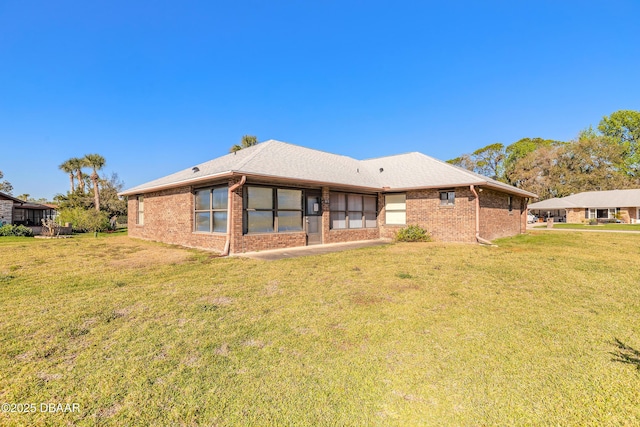 back of property with a lawn and brick siding