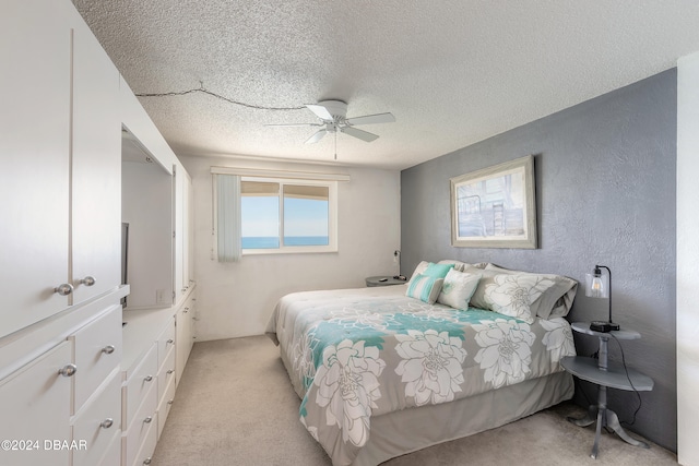 bedroom featuring a textured ceiling, light carpet, and ceiling fan