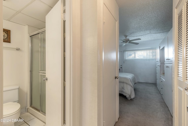 bathroom with ceiling fan, a textured ceiling, toilet, and an enclosed shower