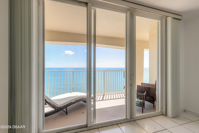 doorway with a healthy amount of sunlight, light tile patterned floors, and a water view