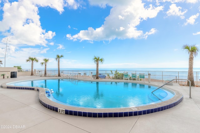 view of swimming pool featuring a patio and a water view