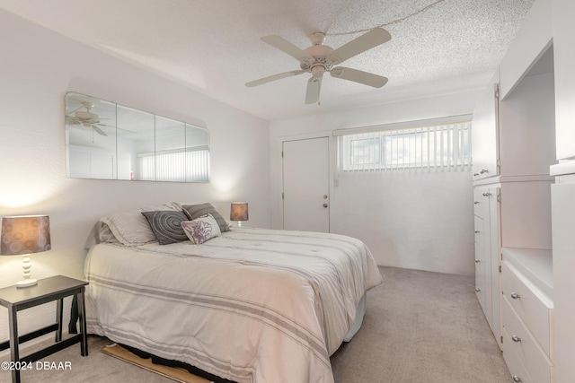 bedroom featuring a textured ceiling, light colored carpet, and ceiling fan