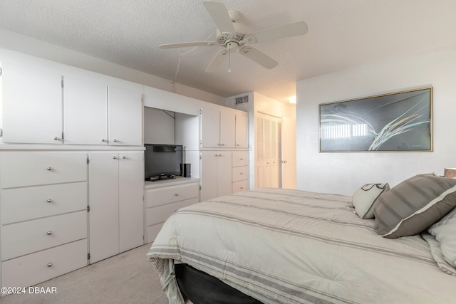 carpeted bedroom with ceiling fan and a textured ceiling