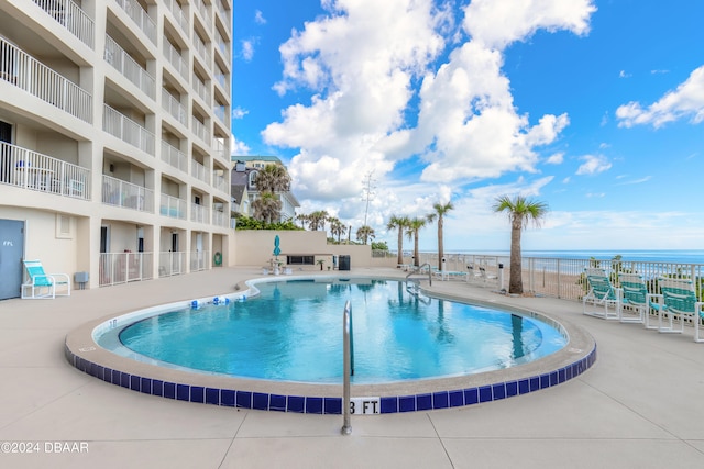 view of pool featuring a water view and a patio area