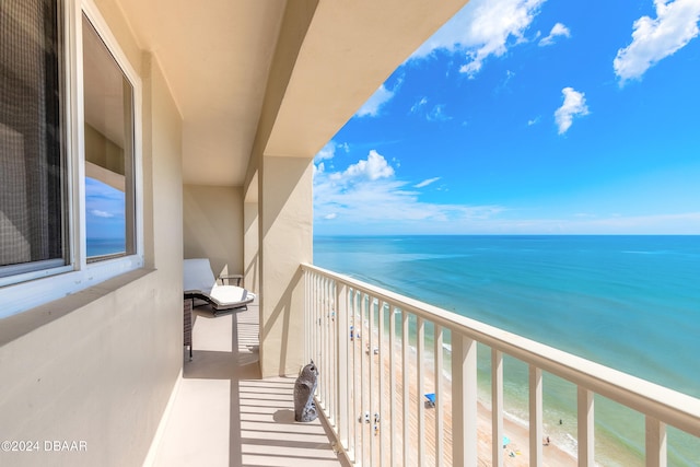 balcony with a water view and a view of the beach