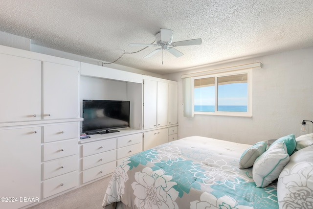 carpeted bedroom with ceiling fan and a textured ceiling